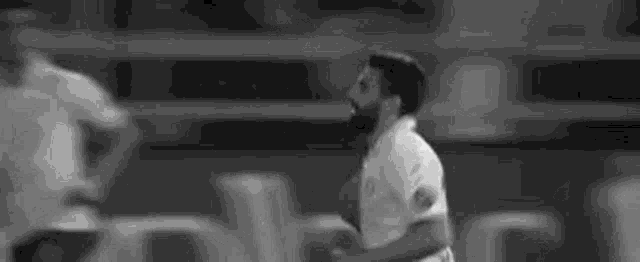 a black and white photo of a soccer player in a white jersey .