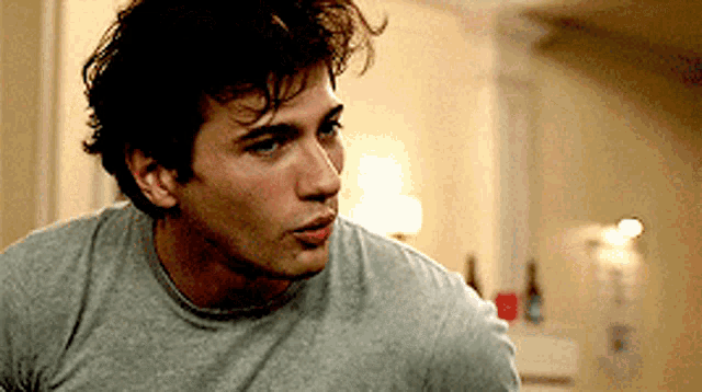 a man in a grey shirt looks to the side