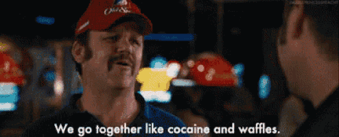a man with a mustache is talking to another man while wearing a hat .