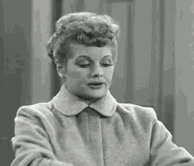 a black and white photo of a woman wearing a coat and earrings .
