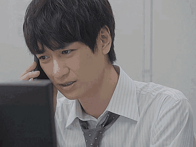 a man in a striped shirt and tie talking on a cell phone