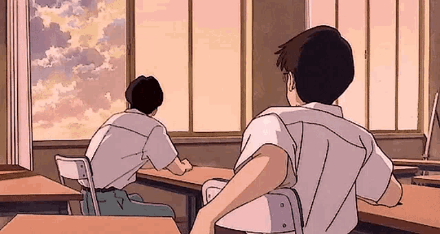 two boys are sitting at desks in a classroom looking out of the window .