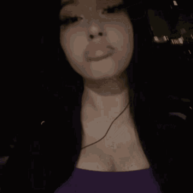 a woman in a purple top is blowing a pink bubble .