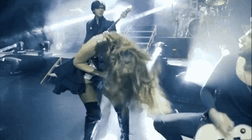 a woman is playing a guitar on a stage while a man plays a bass .
