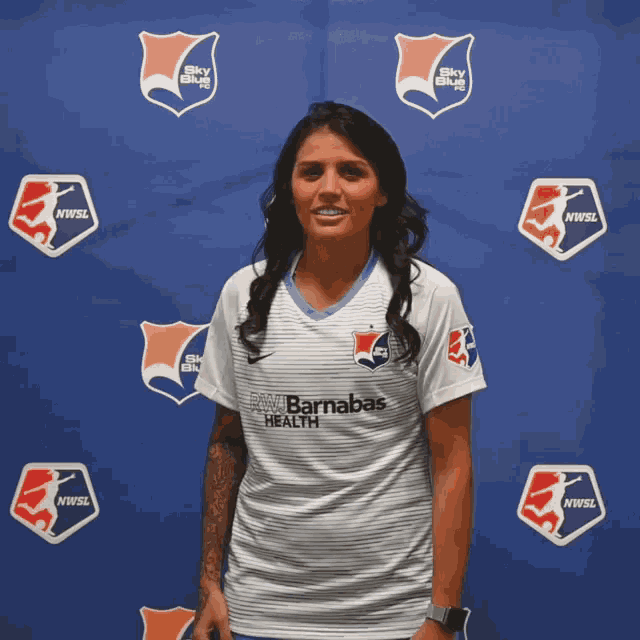 a woman stands in front of a blue backdrop that says nwwsl