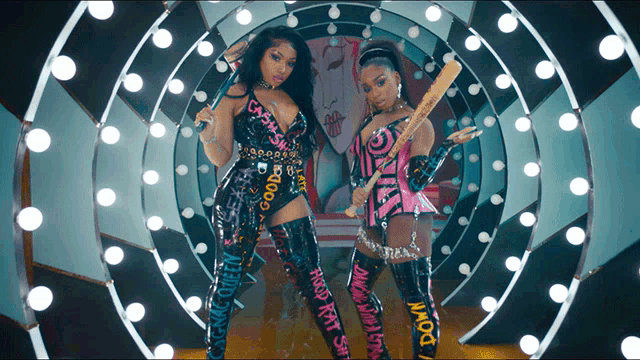 two women standing next to each other with one holding a bat that says " down " on it