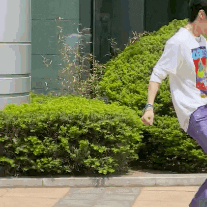 a man wearing a white shirt and purple pants is walking down a sidewalk .