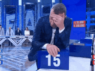 a man in a suit covering his face while playing a game with the number 15