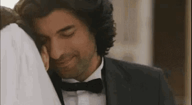 a man in a suit and bow tie is hugging a woman .