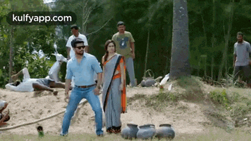 a man and a woman are standing in a field with a group of people standing around them .