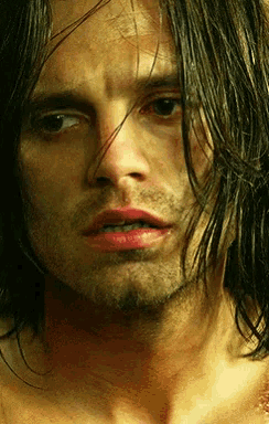 a close up of a man 's face with long dark hair
