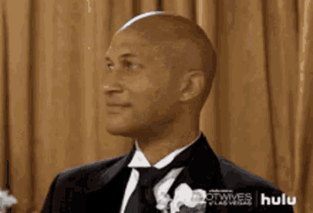 a bald man in a tuxedo and tie is smiling