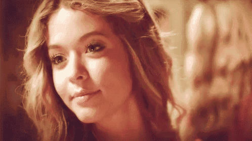 a close up of a woman 's face looking at herself in a mirror .