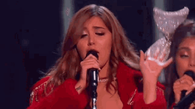 a woman is singing into a microphone on a stage .