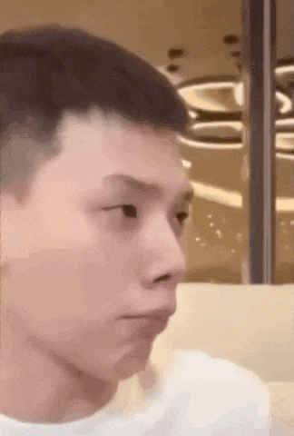 a close up of a young man 's face while sitting at a table .