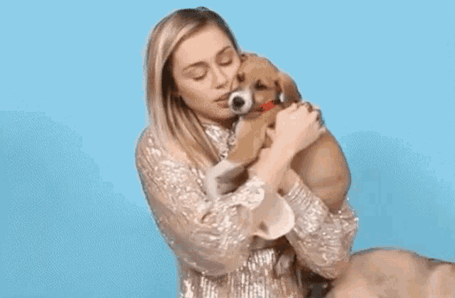 a woman is holding a brown puppy in her arms and kissing it .