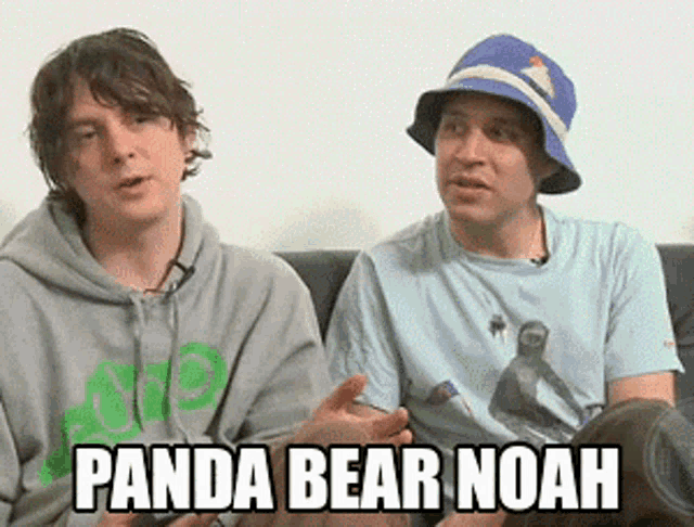two men are sitting on a couch and one of them is wearing a hat that says panda bear noah