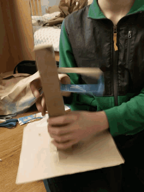 a person in a green jacket is holding a cardboard box