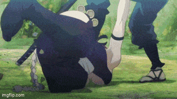 a person is laying on their back in the grass while another person stands next to them .