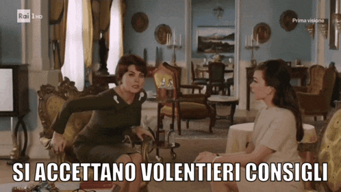 two women are sitting in a living room with the words si accettano volentieri consigli above them