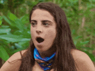 a woman wearing a scarf around her neck is making a surprised face .
