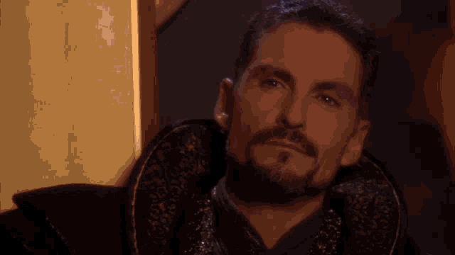 a man with a beard wearing a black and gold coat