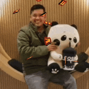 a man is holding a stuffed panda bear that has the letter h on its head
