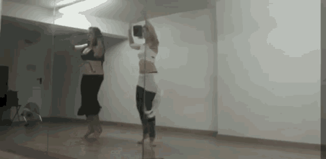 two women are dancing in front of a large mirror .