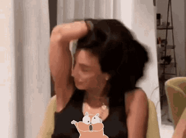 a woman is sitting in a chair with her hand in her hair and a cartoon hamster behind her .