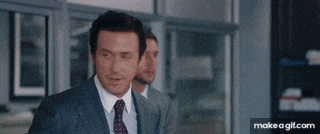 a man in a suit and tie is standing next to another man in an office .