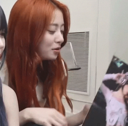 a woman with red hair is looking at a picture of a woman in a pink dress .