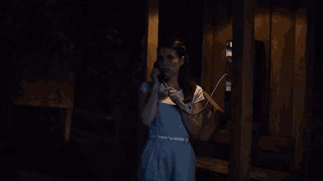 a woman is talking on a payphone with a sticker that says ' telephone ' on it