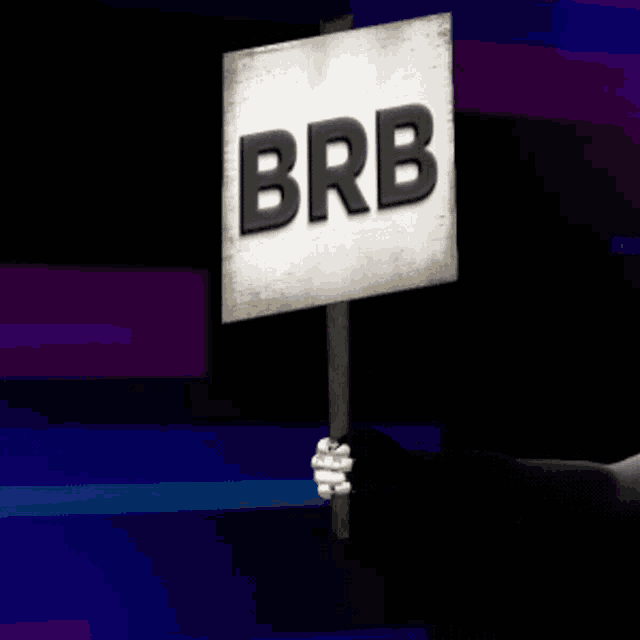 a hand holds up a sign that says brb