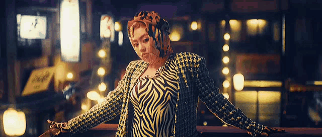 a woman in a zebra print jacket is standing on a railing with her arms outstretched .