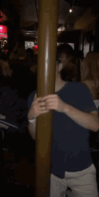 a man wearing a ny hat is standing next to a wooden pole