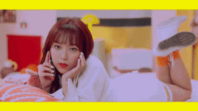 a girl is laying on her stomach on a bed talking on a cell phone