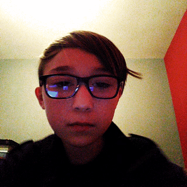 a young boy wearing glasses takes a selfie