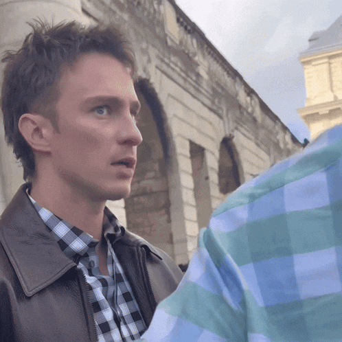 a man wearing a plaid shirt and a brown leather jacket