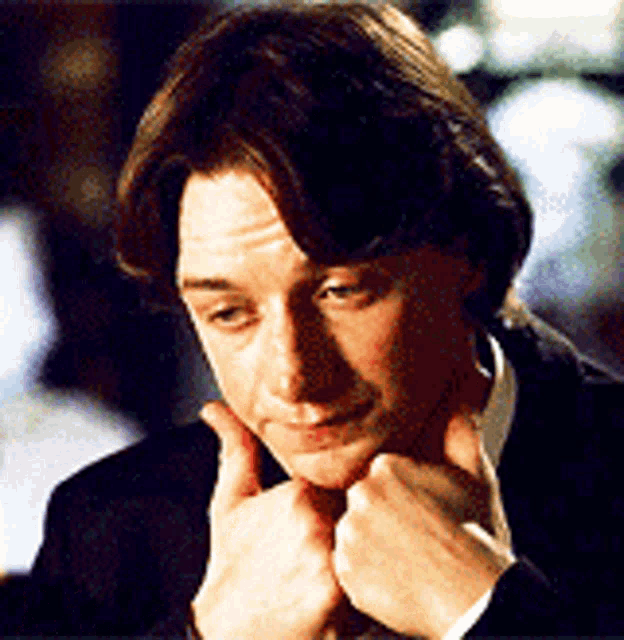 a close up of a man 's face with his hand on his chin