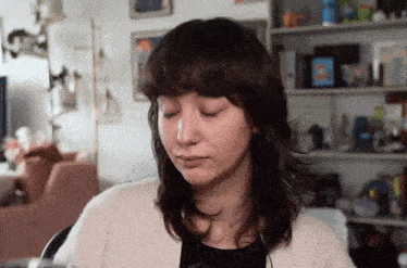 a woman wearing headphones is sitting in front of a shelf