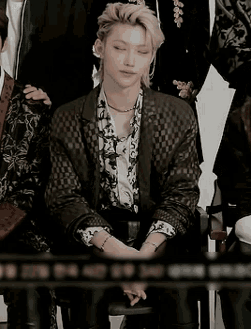a man in a suit sits with his eyes closed in a group photo