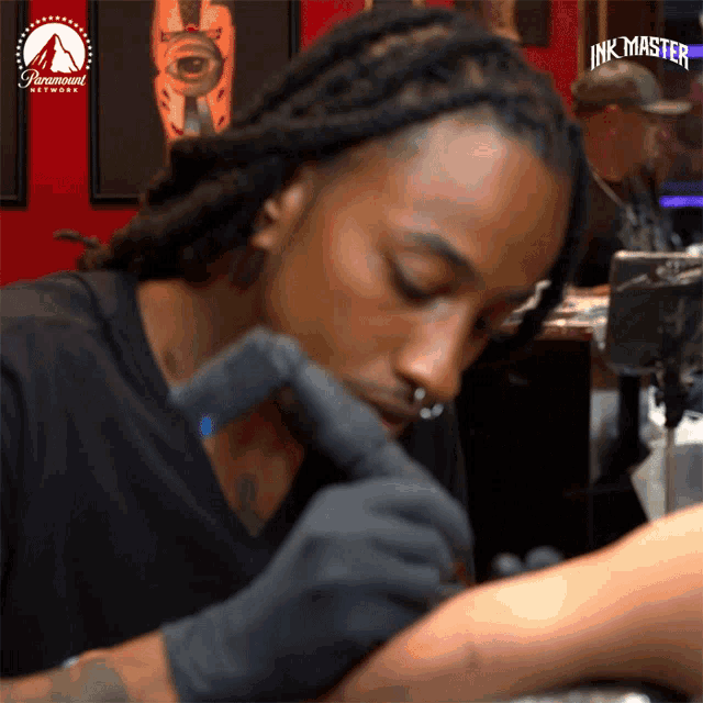 a man is getting a tattoo on someone 's arm with a paramount network logo in the background