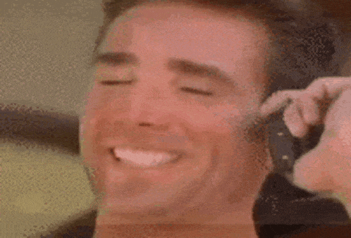 a close up of a man getting his hair cut with a razor while smiling .