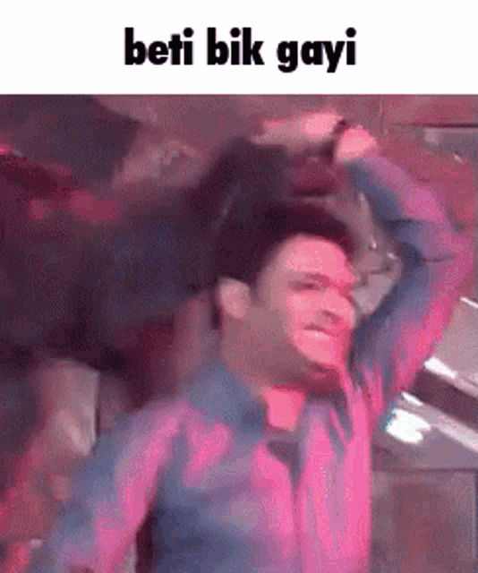 a man in a blue shirt is dancing in a pink room with the words beti bik gayi on the bottom .