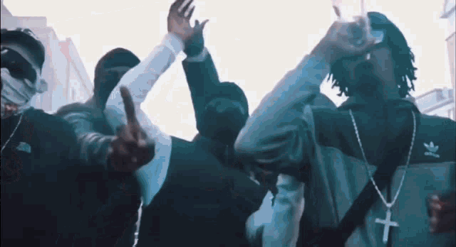 a group of men are standing in a line with their arms in the air .