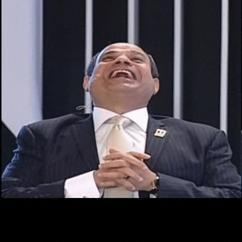 a man in a suit and tie is laughing with his mouth wide open