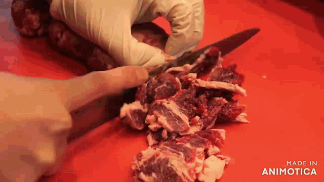 a person is cutting a piece of meat on a red cutting board made in animatica
