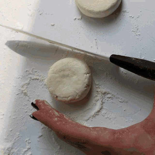 a person is cutting a biscuit with a knife on a table