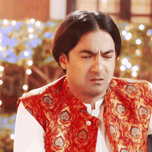 a man wearing a red vest and white shirt is making a face