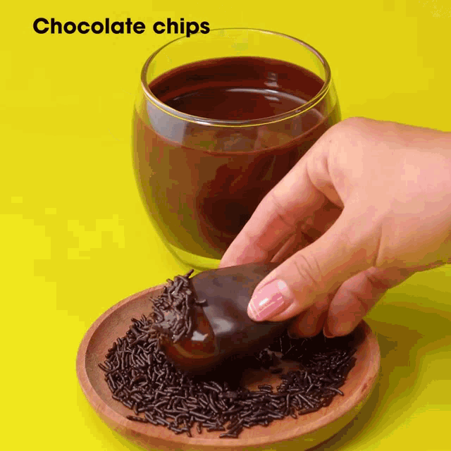 a person dipping a chocolate chip into a cup of chocolate chips